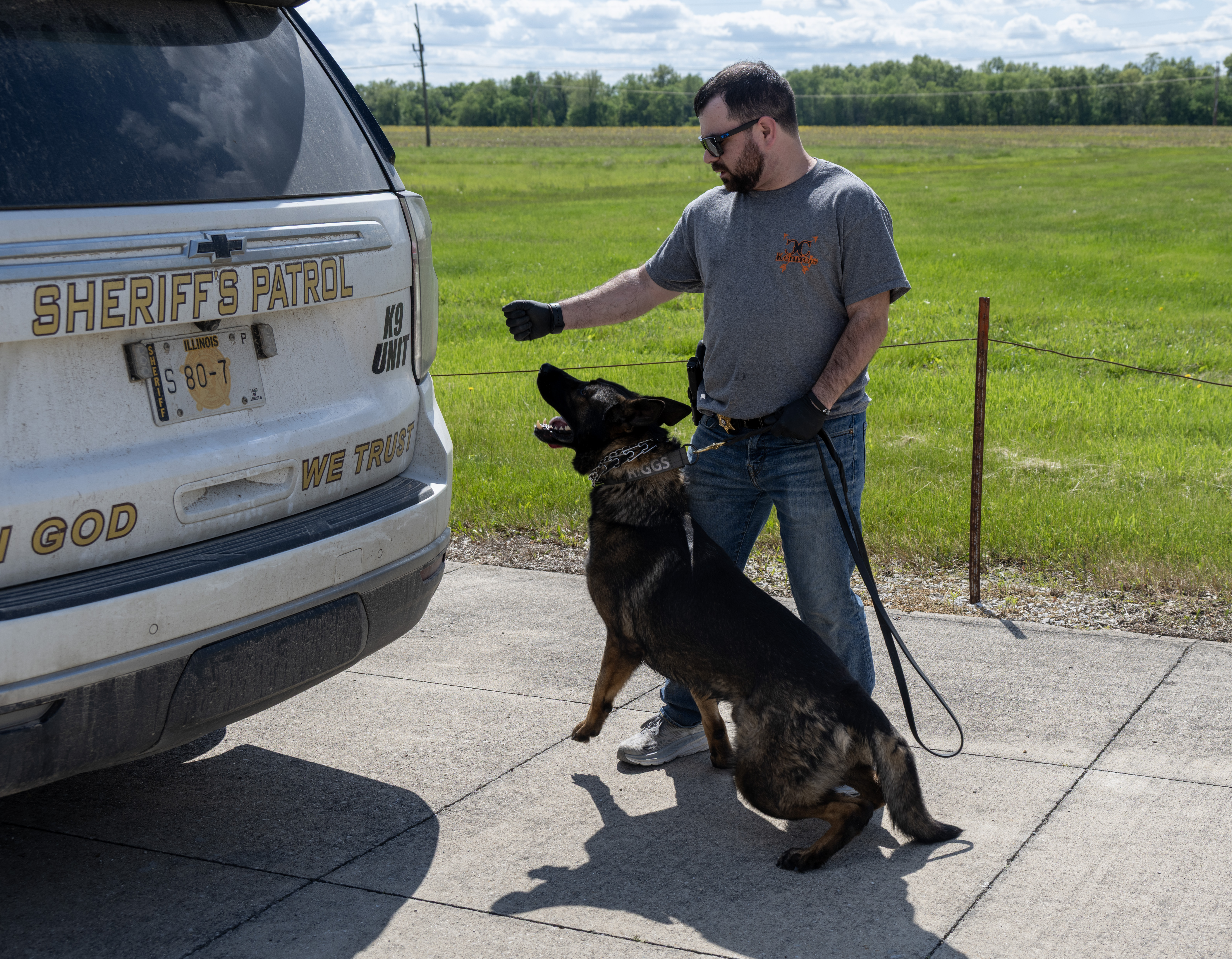 An Administration of Justice instructor conducts a training exercise with a police dog beside a sheriff’s patrol vehicle marked “K-9 Unit” in an outdoor training area.