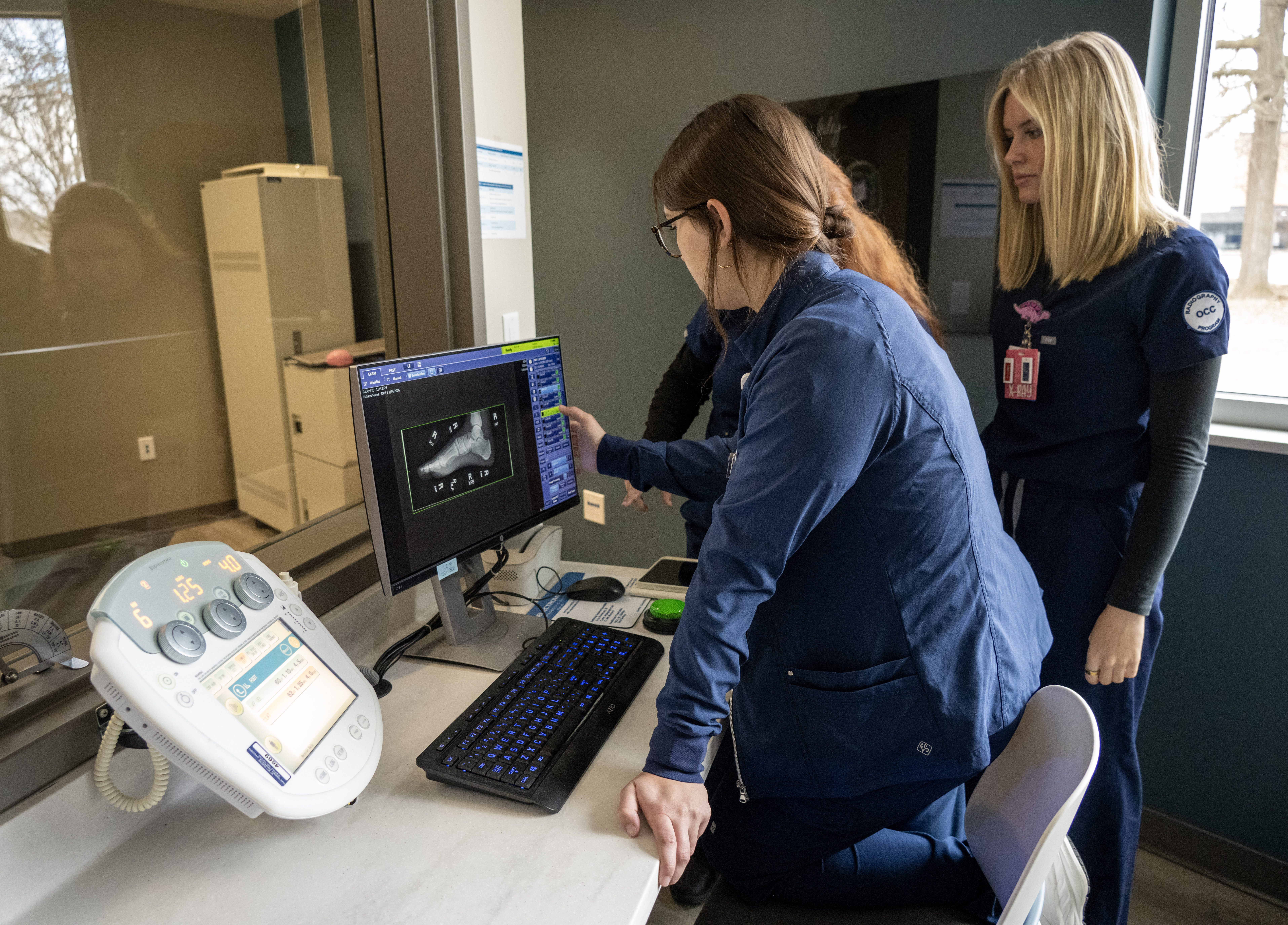 Radiography students review a digital X-ray image on a computer workstation, evaluating imaging results in a clinical simulation environment.